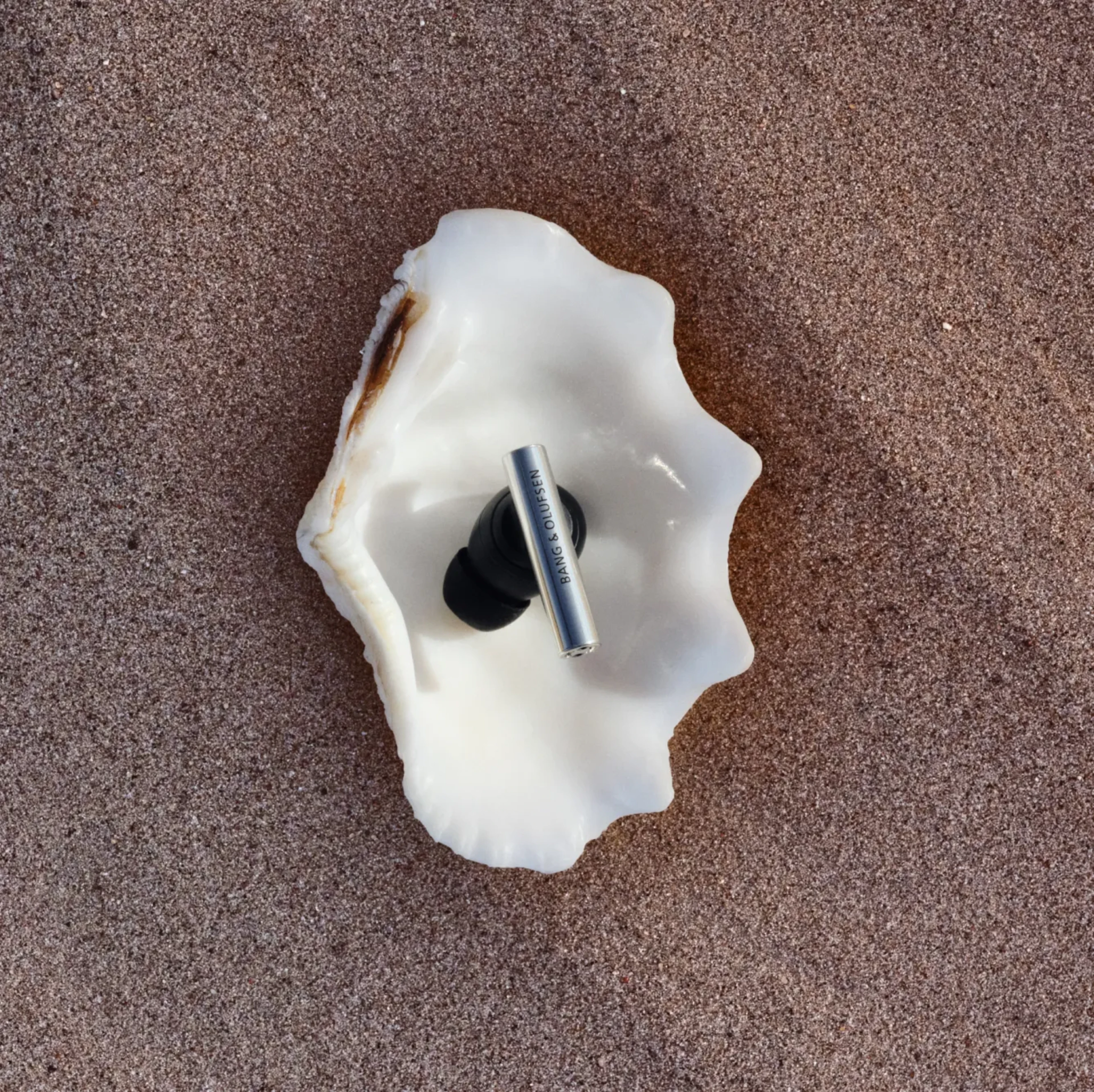 One of Super Hoodie earphone placed on a sea shell